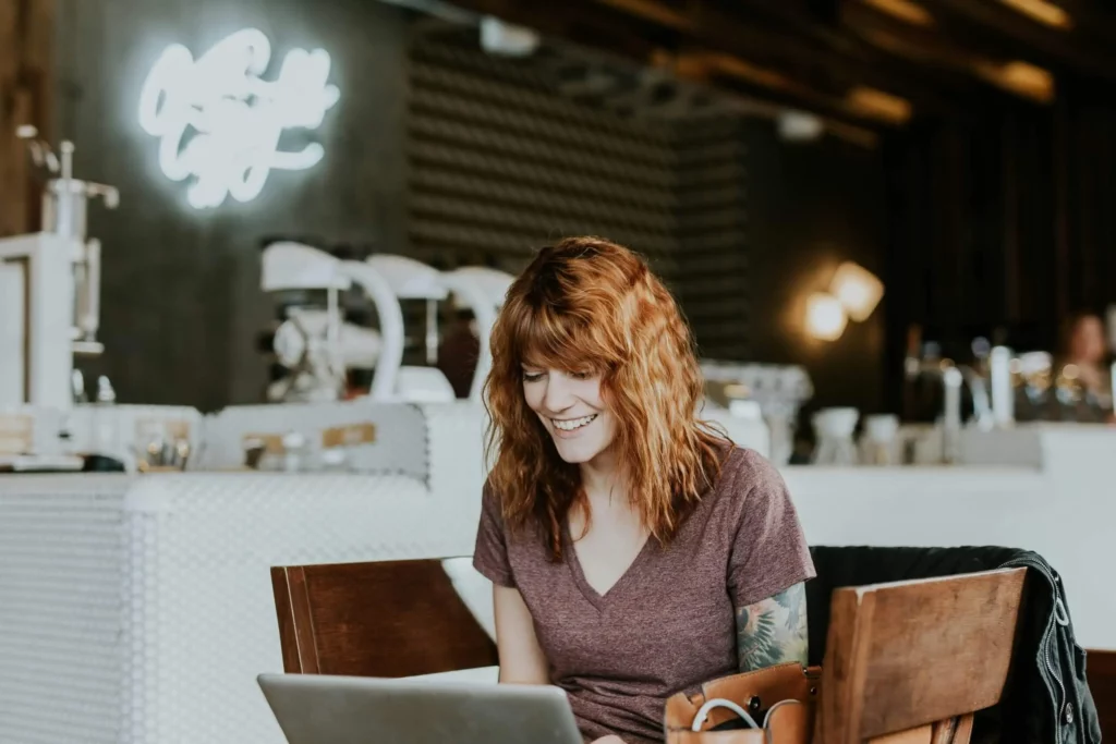 woman smiling copywriting on her laptop at a table